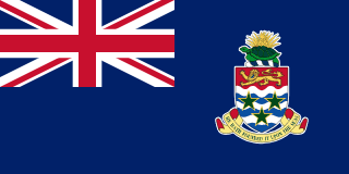 The flag of the Cayman Islands is composed of a blue field with the UK flag in the canton and the national coat of arms centered on the fly half. The coat of arms includes a crest with a pineapple and a turtle above a shield bearing a golden lion. Below are three green stars over white and blue wavy lines. A scroll below the shield bears the motto "HE HATH FOUNDED IT UPON THE SEAS."