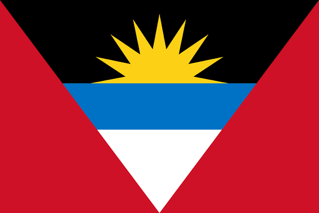 The flag of Antigua and Barbuda has a red field with an inverted isosceles triangle based on the top edge and spanning the height of the field. This triangle has three horizontal bands of black, light blue and white, with the light blue band half the height of the two other bands. The top half of a golden-yellow sun is situated in the lower two-third of the black band to depict a rising sun.