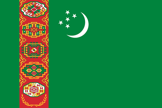 The flag of Turkmenistan has a green field. It features a red vertical band, bearing five carpet guls stacked above two crossed olive branches, near the hoist end of the field. Just to the fly side of the vertical band near the top edge of the field is a hoist-side facing white crescent and five small five-pointed white stars placed just outside the crescent opening.