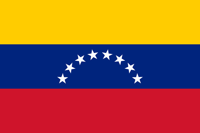 The flag of Venezuela is composed of three equal horizontal bands of yellow, blue and red. At the center of the blue band are eight five-pointed white stars arranged in a horizontal arc.